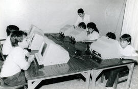 Fotografía con la imagen de estudiantes de primaria recibiendo lecciones de computación en la Esc...