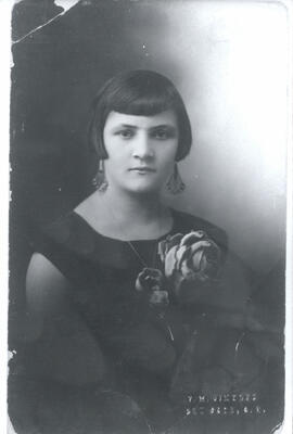 Fotografía de una mujer joven. Se observa: corte de cabello y el gran tamaño de las flores del ve...