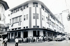 Fotografía del edificio del Registro Civil, calle 6, avenida 4. Se observa una fila de personas u...