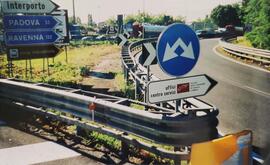 Fotografía de señalización vial italiana del camino a recorrer, destacan varios vehículos al fond...