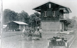 Fotografía del edificio de la estación del ferrocarril en Peralta. Se observa un carro de empuje,...