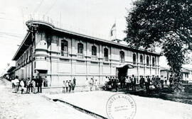 Fotografía de la fachada principal del edificio del Cuartel de Armas. Se observa el parque y un g...