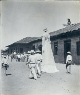 Fotografía de las fiestas de Santa Cruz, Guanacaste. Se observa a la giganta, hombres descalzos, ...