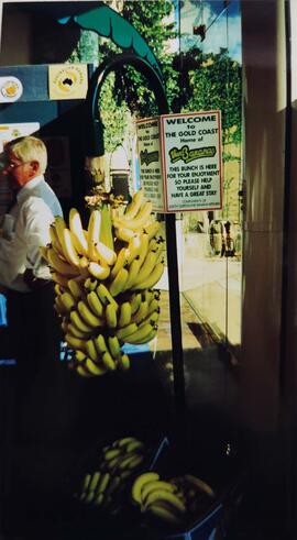 Fotografía de un racimo de banano con un letrero dando la bienvenida a "the gold coast home ...