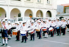 Fotografía de la banda de una escuela en desfile por la calle, con motivo de la celebración de un...