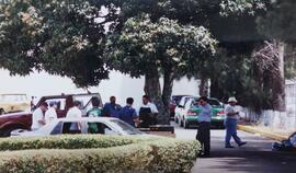 Fotografía de varios colaboradores en el parqueo haciendo fila en un stand, como parte de una act...