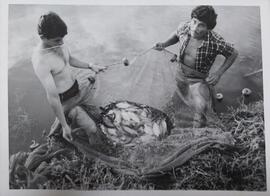 Fotografía de dos hombres pescando tilapias en el estanque creado en 28 Millas, ambos sostienen u...