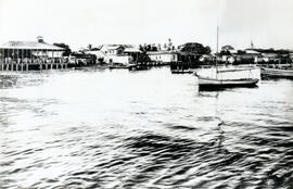 Fotografía de edificaciones de Puntarenas. Se observa el mar, algunas lanchas y al fondo se notan...