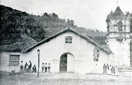 Fotografía de la fachada de la Iglesia de Orosí. Se observan afuera de la misma dos grupos de muj...