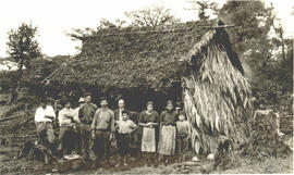 Fotografía de un grupo de personas posando junto a una choza. Se observa: 1 habitantes del lugar ...