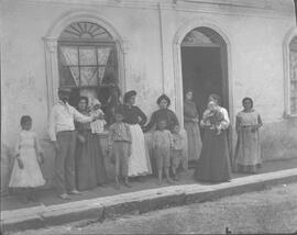 Negativo de un grupo de personas niños, hombres y mujeres. Se observa el vestuario de la época. A...