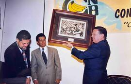 Fotografía de Victor Herrera, en el medio, y de Miguel Ángel Rodríguez con un cuadro en sus manos...