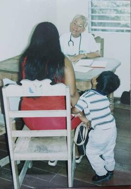 Fotografía de funcionaria médica atendiendo a una madre y su hijo en la feria de salud en Proyect...