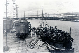 Fotografía del Puerto de Limón. Se observan algunos vagones del ferrocarril, una embarcación en l...