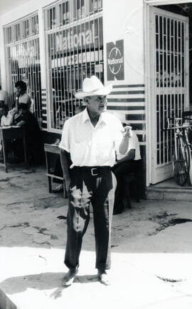 Fotografía con la imagen de un anciano descalzo y con sombrero, localizado diagonal al parque cen...