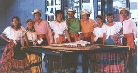 Fotografía de miembros del grupo de bailes folclóricos del Archivo Nacional frente a la maqueta d...