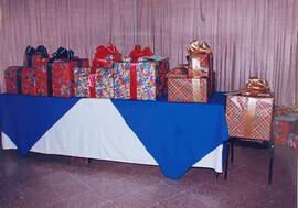 Fotografía de una mesa con manteles que tiene regalos para los niños becados, actividad del Conse...