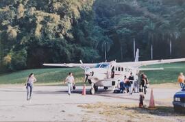 Fotografía de una avioneta con varias personas sacando equipaje de ella, entre ellos se encuentra...