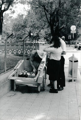 Fotografía con la imagen de un vendedor de copos preparando el producto a unos estudiantes de sec...